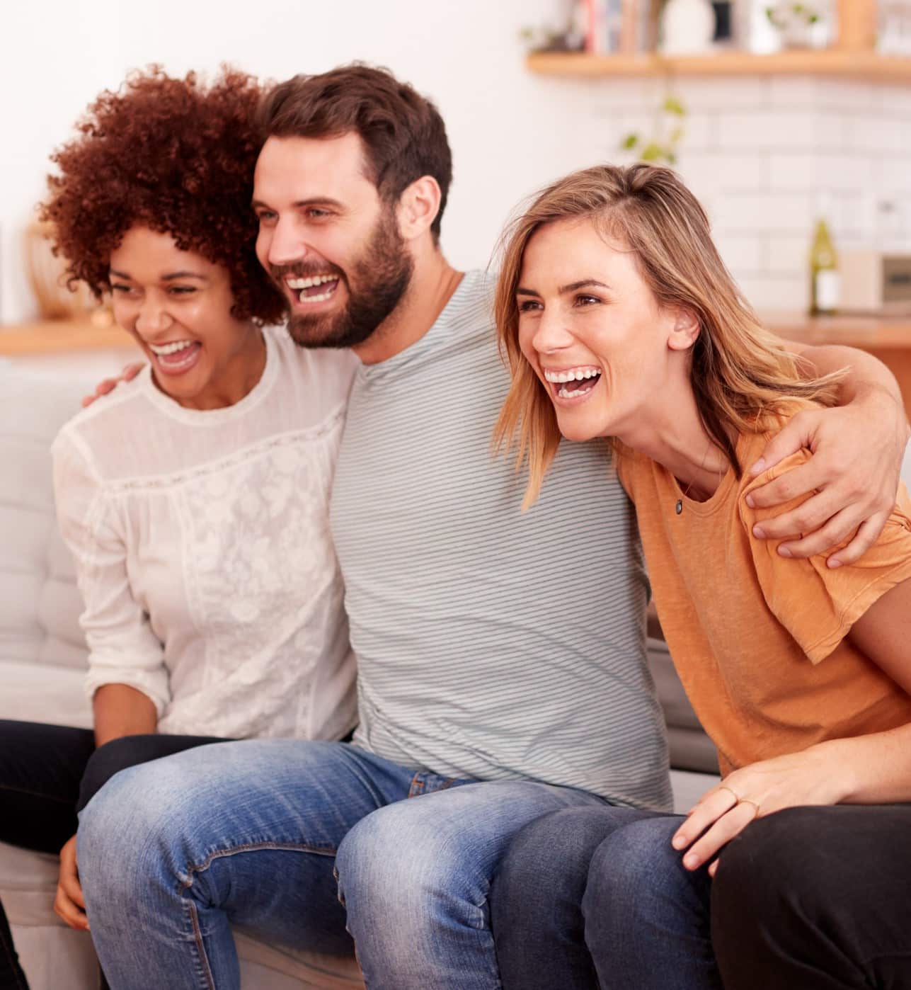 Three People sitting on a couch laughing