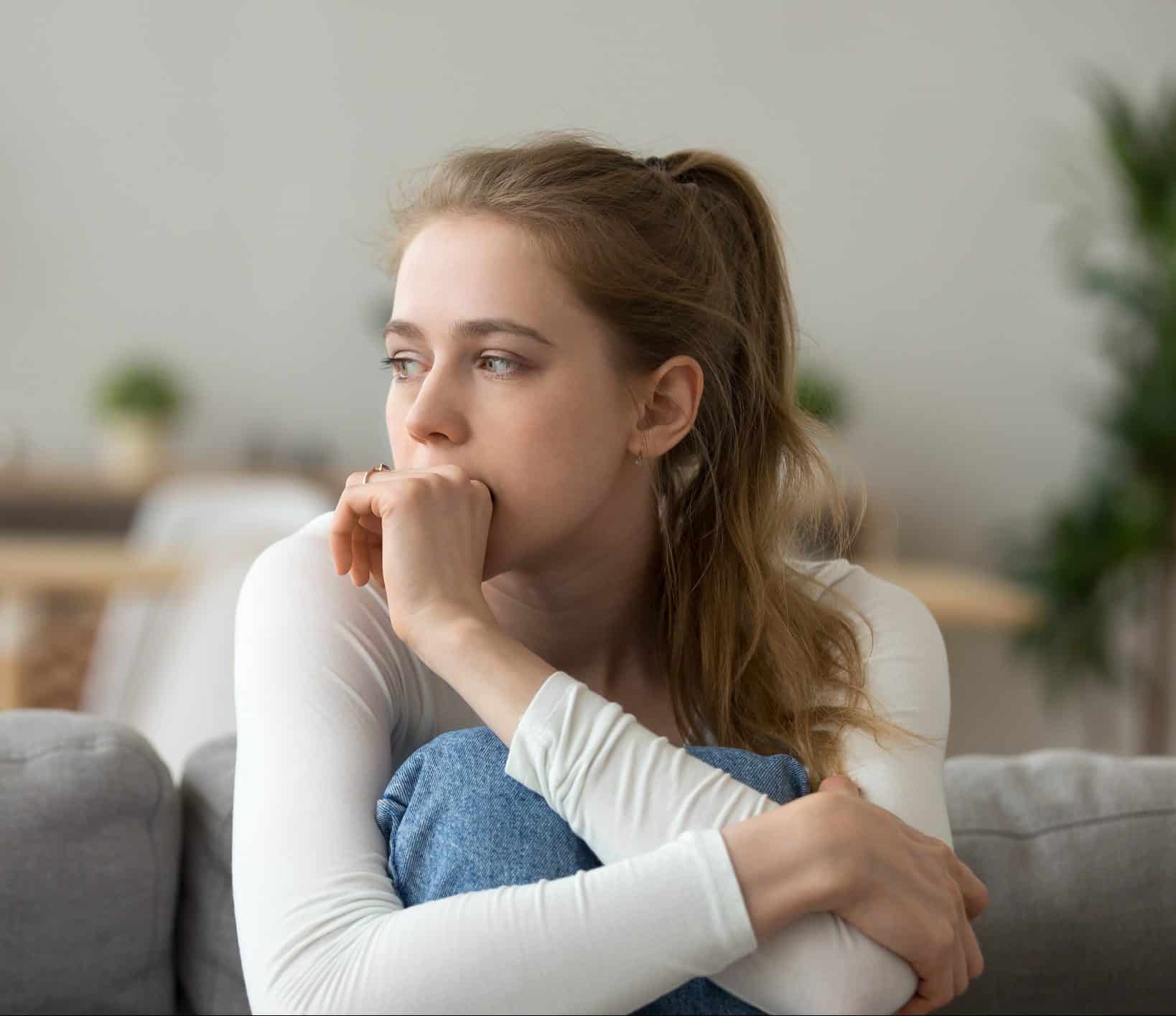 A young woman sitting with her knees tucked up and her arms wrapped around them